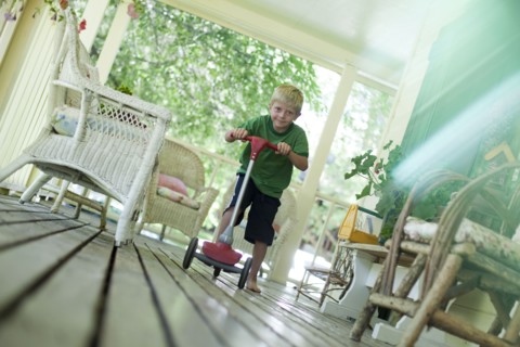 Little boy riding scooter on porch. Photo : Tim Pannell