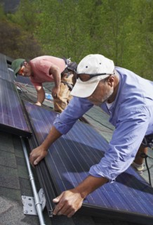 Construction workers installing solar panels on roof. Photo : Shawn O'Connor
