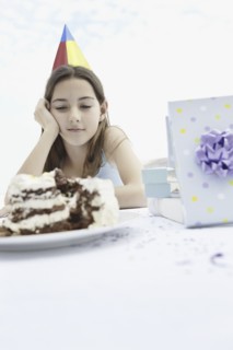 Young girl staring at birthday cake. Photo : momentimages