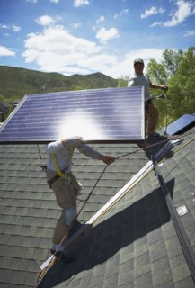 Construction workers installing solar panels on roof. Photo : Shawn O'Connor