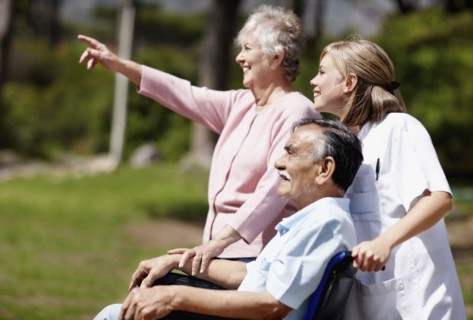 Two woman out for a walk with man in a wheelchair. Photo : momentimages