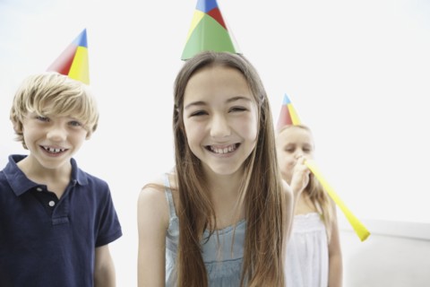 Three children wearing birthday hats. Photo : momentimages