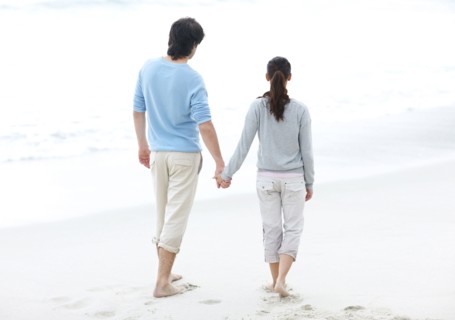 Couple walking barefoot on the beach. Photo. momentimages
