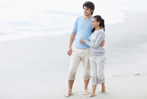 Couple walking barefoot on the beach. Photo : momentimages