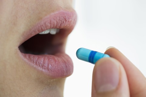 Woman putting capsule in her mouth.