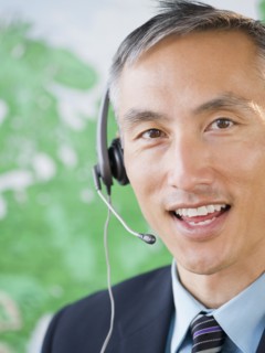 Businessman with headset looking at camera and smiling, studio shot. Photo : Jamie Grill