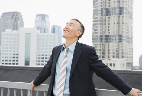 Happy businessman standing outdoors with eyes closed. Photo : Jamie Grill