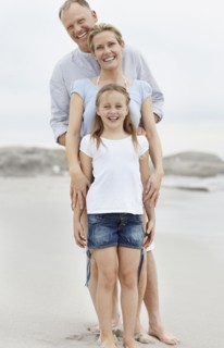 Girl (10-11) playing on beach with parents. Photo : Momentimages