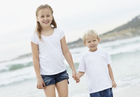Girl (10-11) and boy (4-5) on beach. Photo : Momentimages