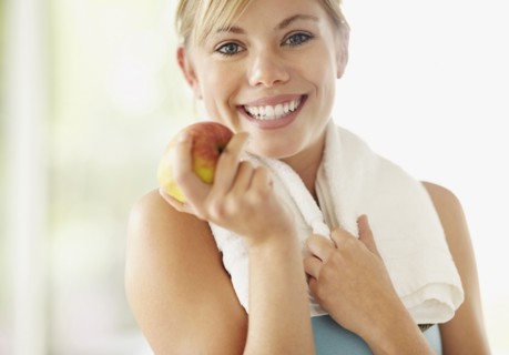 Portrait of young blonde woman holding apple. Photo : Momentimages