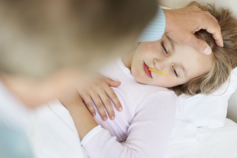 Grandfather tending granddaughter (10-11) lying in bed with thermometer in mouth. Photo :
