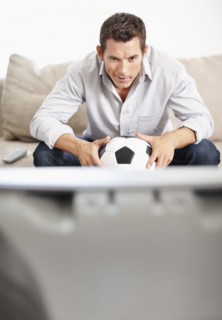 Mid adult man watching football match on television. Photo : Momentimages
