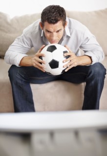 Mid adult man watching football match on television. Photo : Momentimages