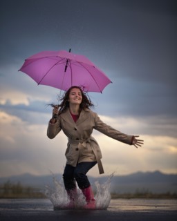 Young woman with umbrella under overcast sky. Photo : Mike Kemp