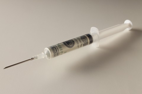 Studio shot of syringe with dollar banknote. Photo : Mike Kemp