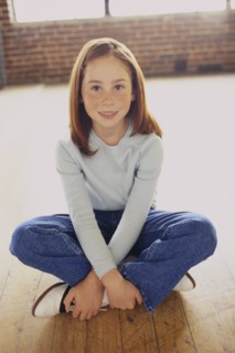 Cute young girl sitting cross legged. Photo : Fisher Litwin
