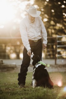 Cowboy feeding dog on ranch. Photo : Mike Kemp