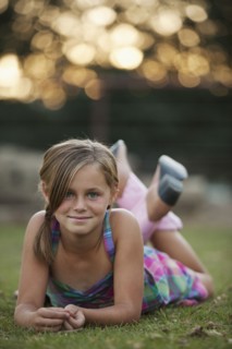Portrait of girl (8-9) lying on grass. Photo : Mike Kemp