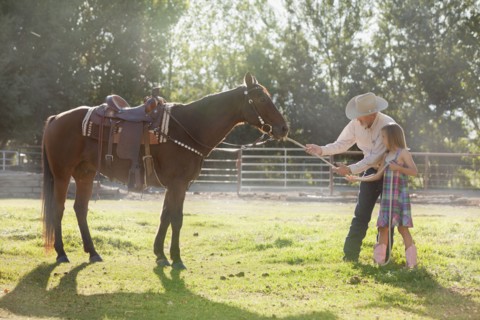 Senior man with granddaughter (8-9) training horse in ranch. Photo : Mike Kemp