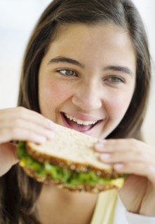 Girl (12-13) eating sandwich.