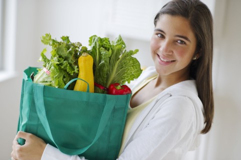 Portrait of girl (12-13) holding groceries .