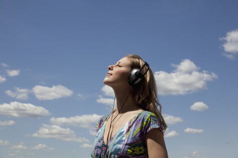 Young woman listening to music outdoors. Photo : Johannes Kroemer