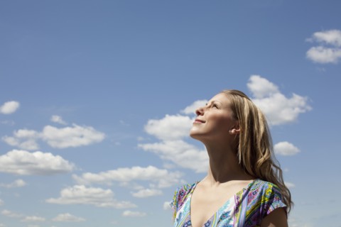 Young woman smiling against cloudy sky. Photo : Johannes Kroemer