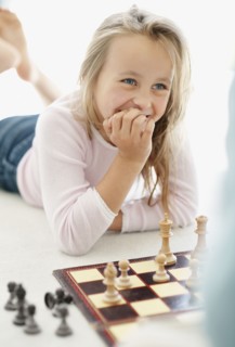 Girl (10-11) playing chess. Photo : Momentimages