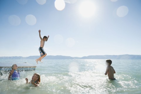 Kids (6-7,8-9,10-11,12-13) playing on raft on lake.