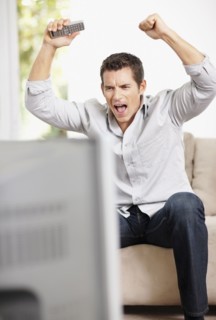 Man cheering in front of television. Photo : Momentimages