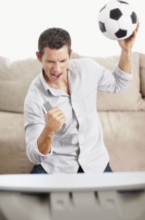 Mid adult man watching football match on television. Photo : Momentimages