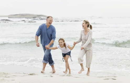 Girl (10-11) playing on beach with parents. Photo : Momentimages
