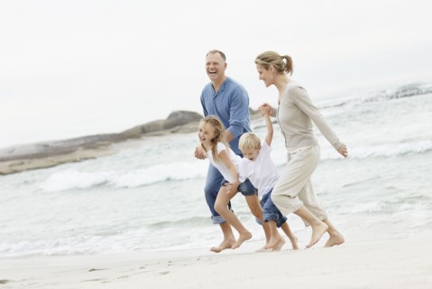 Girl (10-11) and boy (4-5) playing on beach with parents. Photo : Momentimages