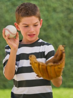 Boy (10-11) holding baseball and baseball glove. Photo : Daniel Grill