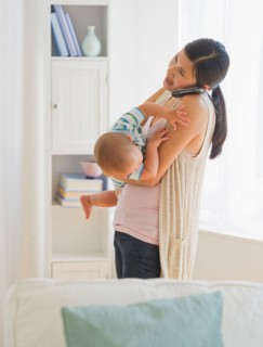 Mother carrying son (6-11 months) and talking on phone. Photo : Daniel Grill