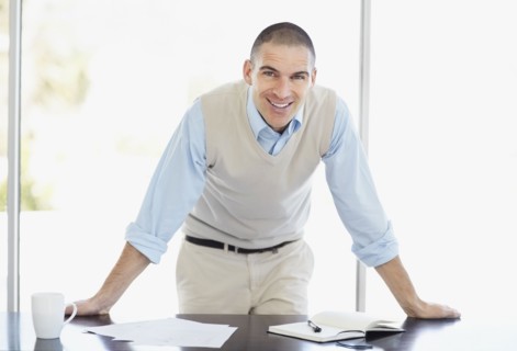 Cheerful office worker with hands behind back. Photo : Momentimages