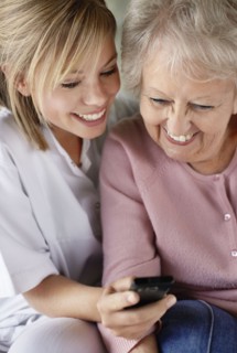 Daughter and mother checking mobile phone and smiling. Photo : Momentimages