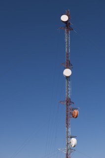 Tele-communications relay tower against blue sky.