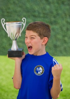 Boy (10-11) holding trophy and cheering. Photo : Daniel Grill