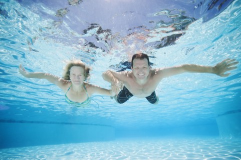 Mid adult couple swimming underwater.