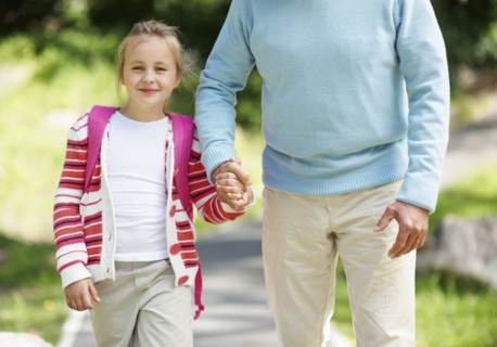 Granddaughter (10-11) and grandfather walking through parkholding hands. Photo : Momentimages