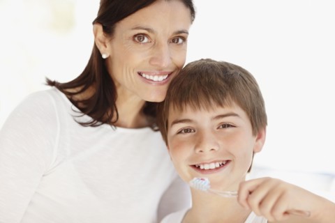 Mother embracing son (12-13)  while he is brushing teeth. Photo : Momentimages