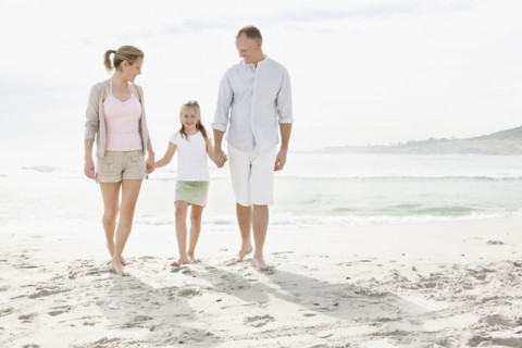 Girl (10-11) playing on beach with parents. Photo : Momentimages