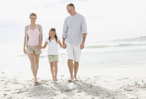 Girl (10-11) playing on beach with parents. Photo : Momentimages