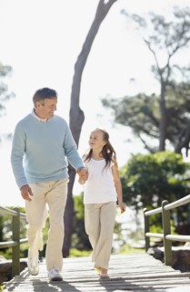 Granddaughter (10-11) and grandfather walking on bridgeholding hands. Photo : Momentimages