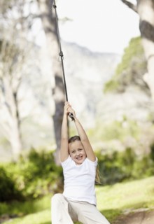 Girl (10-11) swinging on rope. Photo : Momentimages