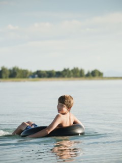 Boy (12-13) floating on rubber ring on lake.