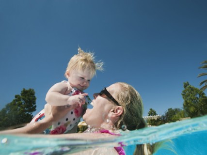 Mother and daughter (12-18months) playing at swimming pool.