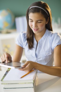 Schoolgirl (12-13) using digital tablet.