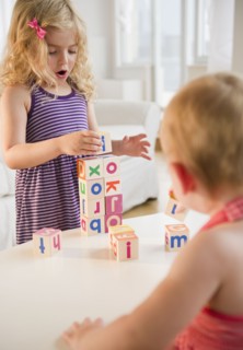 Girls (18-23 months, 4-5) playing with blocks and looking at camera. Photo : Jamie Grill